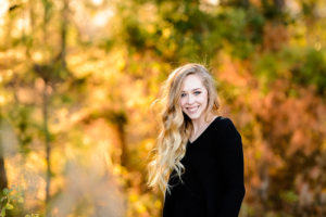 Young blond in black shirt with fall colors in background