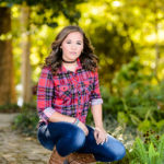 Brunette with choker and plaid shirt poses outdoors