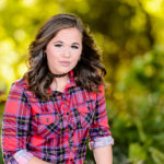 Brunette with choker and plaid shirt poses outdoors