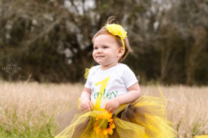 girl with blonde hair in yellow tutu sits in field- macon photographer