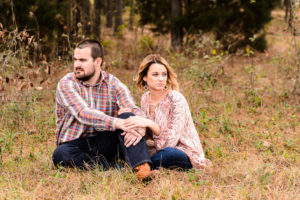 couple sitting in field for engagement session in middle georgia