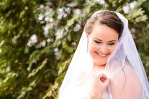 middle georgia wedding, bride holding white veil by face during bridal portait in garden