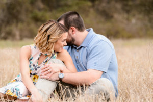 couple sitting in field at tryphenas garden wedding venue middle georgia engagement session