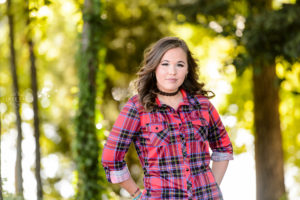 girl standing in field wearing red shirt and blue jeans for senior portrait session