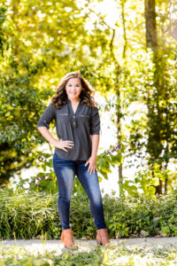 brown haired girl wearing blud jeans and gray shirt standing and laughing for senior portrait session in middle georgia