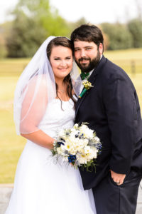 middle georgia wedding, bride and groom standing beside each other cheek to cheek smiling and holding bridal bouquet