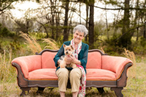 lady in green shirt sitting on sofa in field holding puppy for portrait session middle georgia